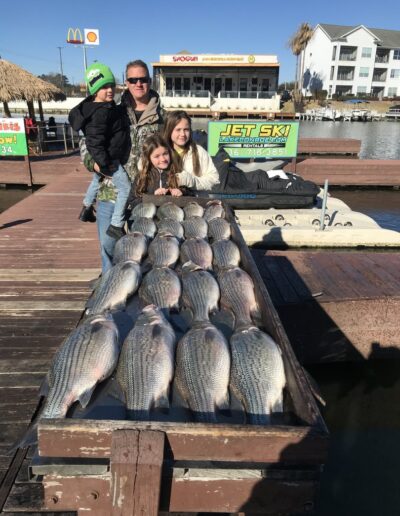 A family posing with some fish on the dock.