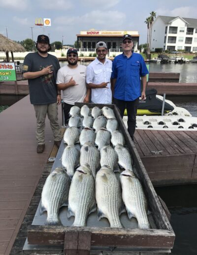 A group of men standing next to fish on the water.