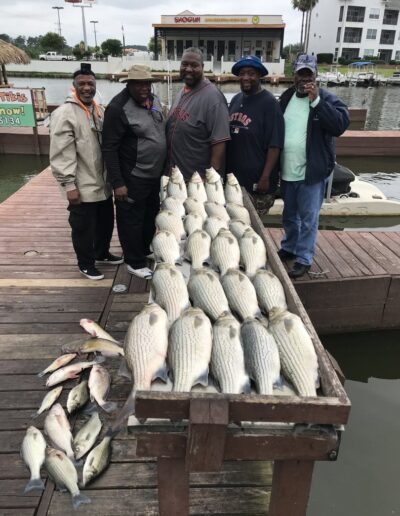 A group of people standing next to fish on the water.
